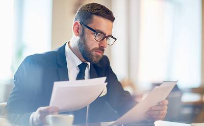 Confident banker reading financial papers while sitting in cafe